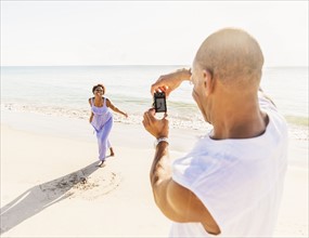 Man photographing woman on beach