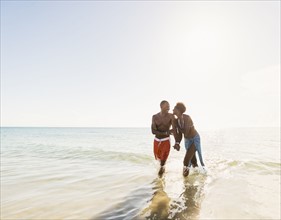 Man and woman holding hands on beach