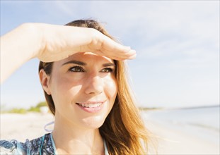 Woman shielding eyes on beach