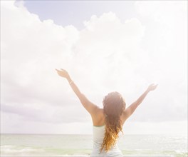 Woman with arms raised standing on beach