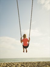 Girl (4-5) swinging on beach