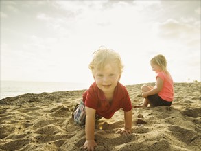 Girl (4-5) and boy (2-3) playing on beach