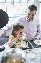 Father and daughter (4-5) eating together in dining room