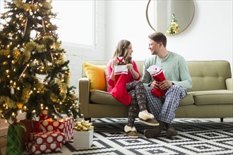 Young couple with Christmas stockings on sofa