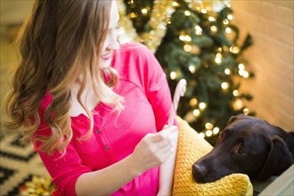 Woman showing candy cane to chocolate Labrador at Christmas