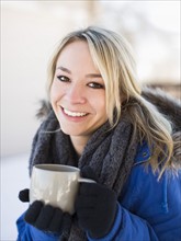 Portrait of woman holding coffee mug outdoors in winter