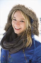 Portrait of smiling young woman in winter coat hood