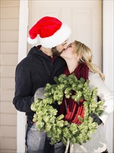 Young couple holding wreath and kissing
