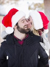 Portrait of young couple in santa hats, piggyback