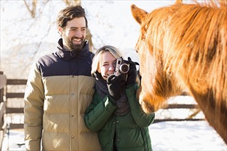 Young couple photographing horse
