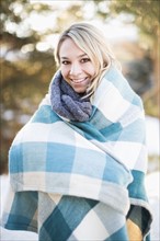 Portrait of woman wrapped in blanket standing outdoors