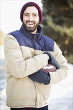 Portrait of man holding football outdoors