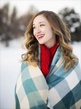 Portrait of woman wrapped in blanket smiling outdoors