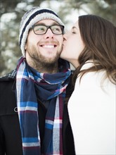 Woman kissing man's cheek outdoors