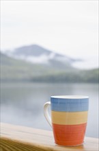 Close-up of mug on balustrade, lake in background