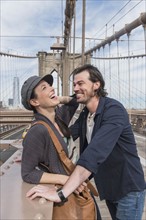 Happy couple flirting on Brooklyn Bridge. Brooklyn, New York.