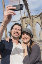 Happy couple taking selfie on Brooklyn Bridge. Brooklyn, New York.