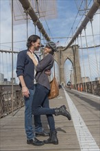 Happy couple embracing on Brooklyn Bridge. Brooklyn, New York.