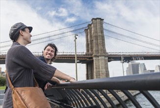 Couple leaning against railing. Brooklyn, New York.