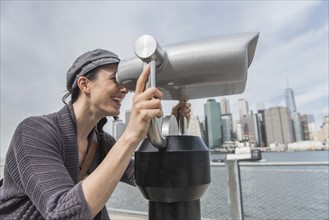 Woman watching through coin-operated binoculars. Brooklyn, New York.