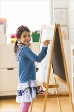 Portrait of girl (6-7) writing on board in classroom.