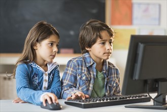 Pupils (6-7) using computer in classroom.
