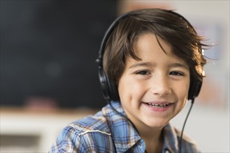 Portrait of smiling schoolboy (6-7) in headphones.
