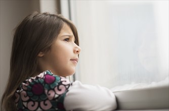 Girl (6-7) looking out of window.
