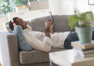 Man relaxing on sofa with tablet pc. .