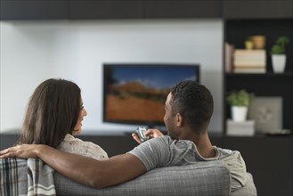 Couple sitting in living room and watching TV.