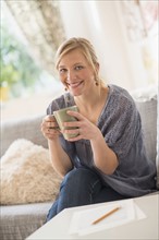 Woman sitting on sofa and drinking coffee.