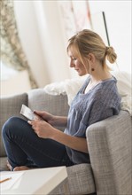 Pensive woman sitting on sofa with tablet pc.