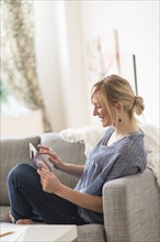 Smiling woman sitting on sofa with tablet pc.