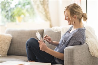 Woman sitting on sofa and using tablet pc.