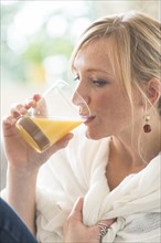 Woman sitting in living room and drinking orange juice.