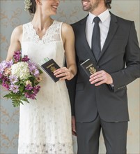 Happy bride and groom posing with passports.