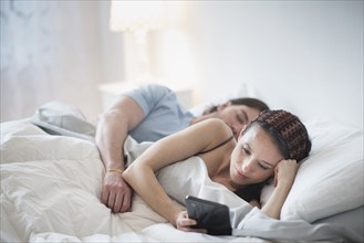 Couple in bed, Man sleeping, Woman using tablet pc.