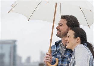 Side view of couple under umbrella.