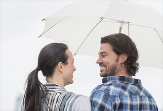 Rear view of couple under umbrella.
