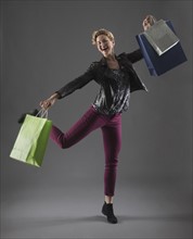 Studio shot of cheerful woman holding shopping bags.