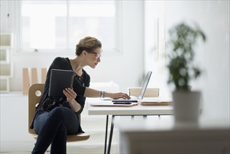 Businesswoman using laptop in office.