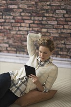 Young woman lying on floor and using digital tablet.
