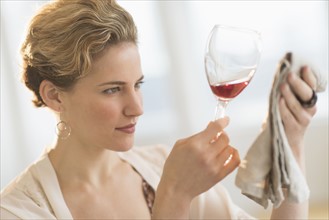 Young woman looking closely at red wine. .
