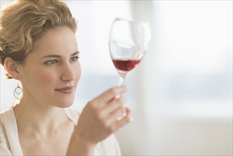 Young woman examining red wine.