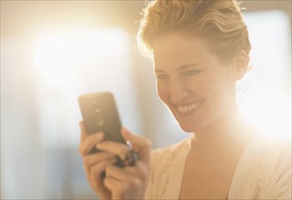 Smiling young woman using mobile phone.