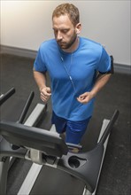 Mid adult man exercising on treadmill.