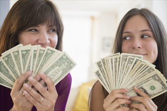 Teenage girl (14-15) and her mom holding dollar bills