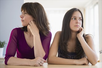 Frustrated teenage girl (14-15) and her mom sitting at table