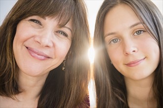 Portrait of smiling mom and daughter (14-15) indoors