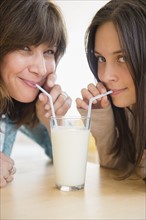 Teenage girl (14-15) drinking milk with her mom at home